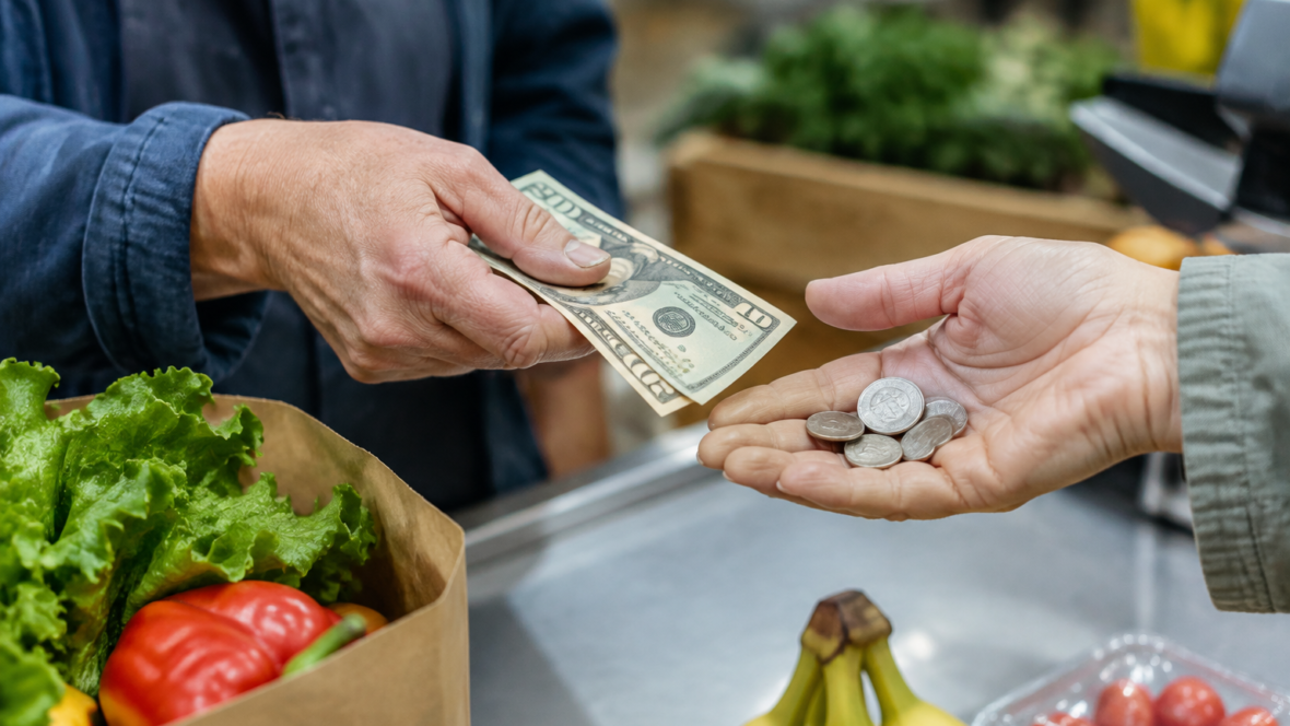 руки передають гроші через прилавок у продуктовому магазині