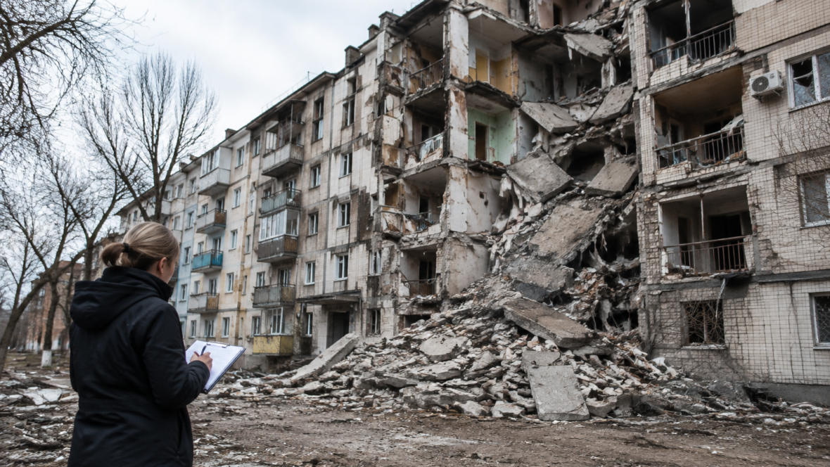 Пошкоджений житловий будинок, людина з бланком фіксує пошкодження