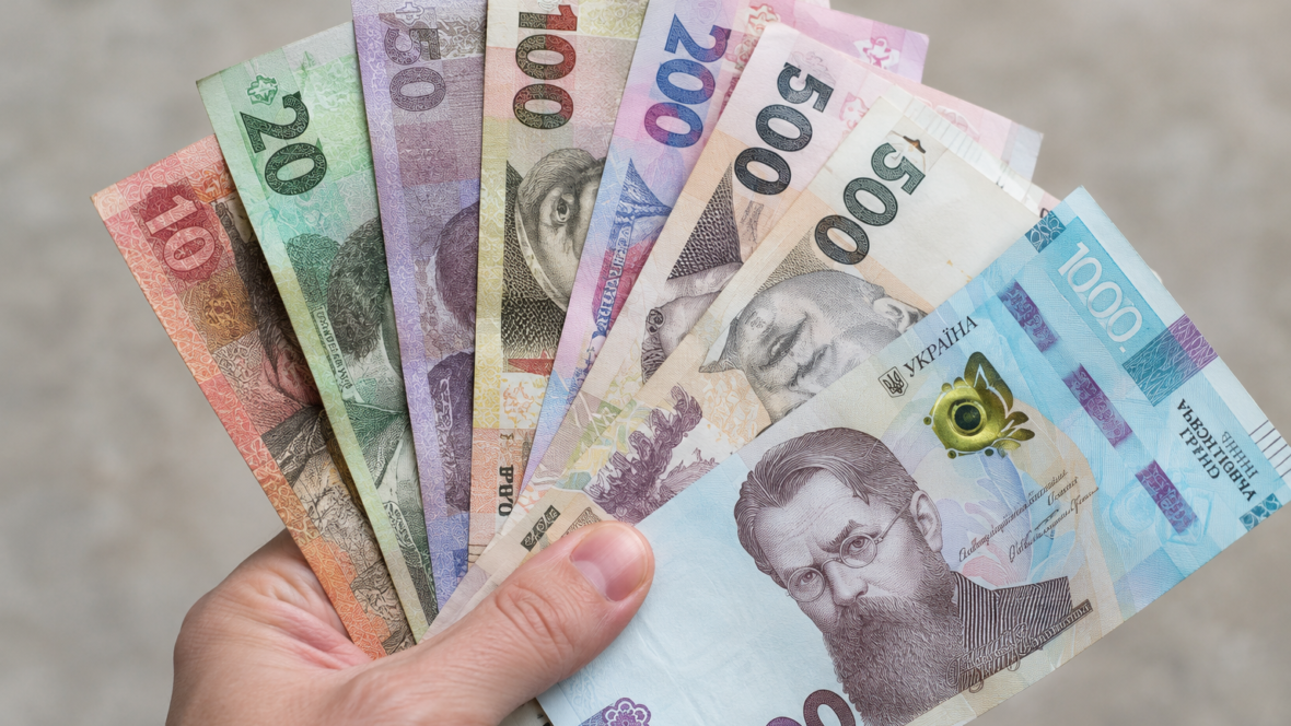 рука тримає старі і нові купюри 20, 50, 100, 200, 500 грн