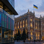 Фасад банку та інфоекран фондової біржі у вечірньому світлі